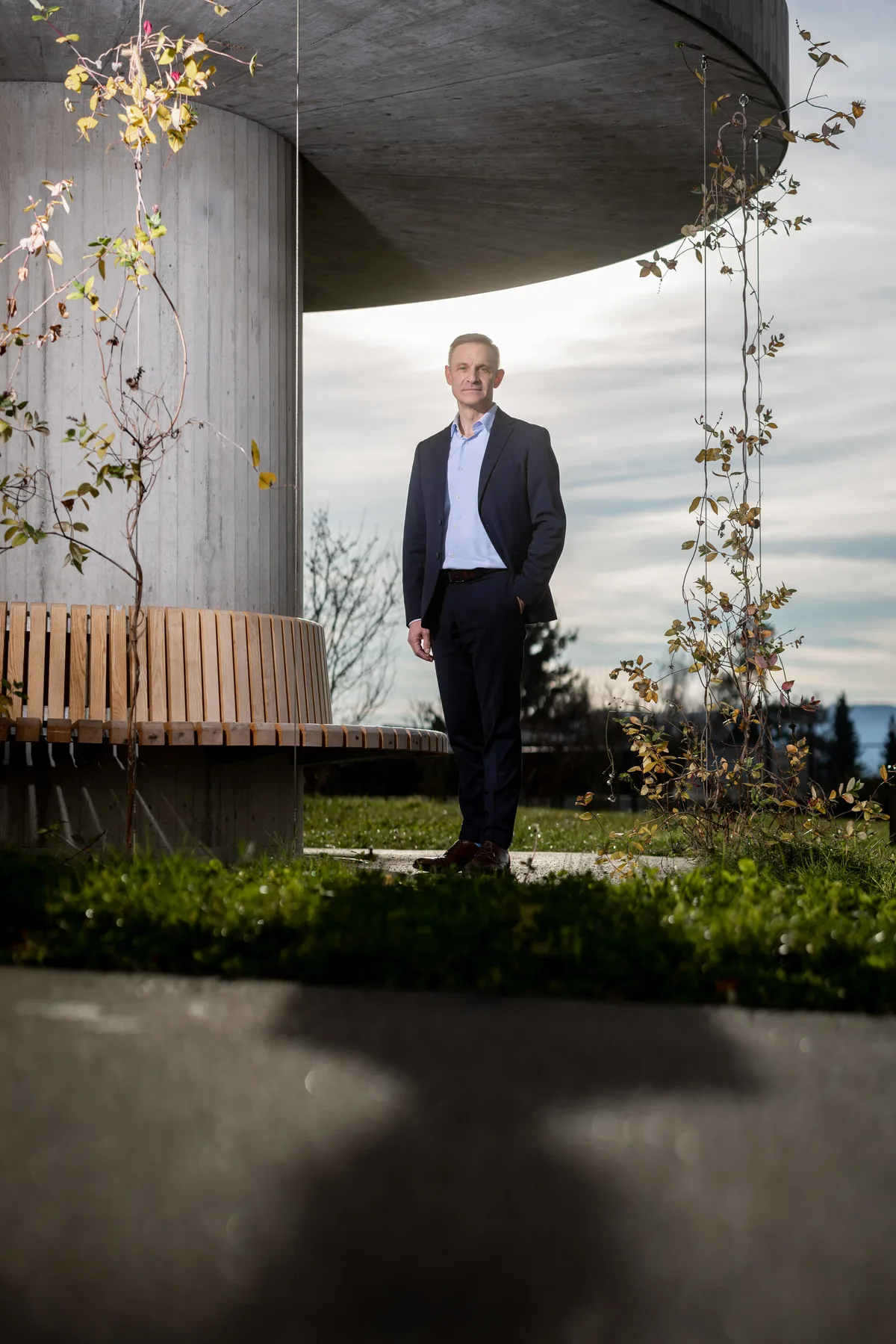 Ein Mann steht in einem Park neben einer runden Bank. 